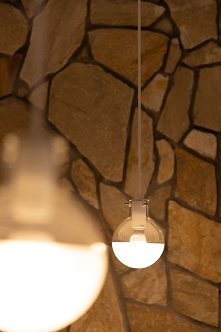 石調の壁面を背景に、ペンダント照明で空間を演出した店舗内装デザイン