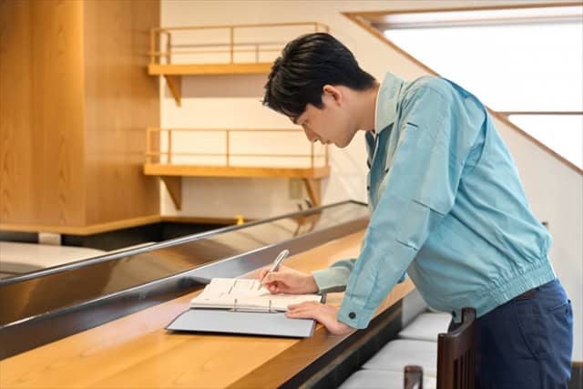 店舗カウンターで書類に記入しながら内装工事や開業準備の確認をしているスタッフの様子