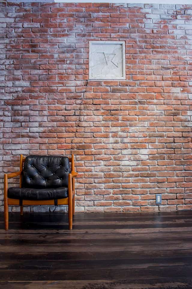 レンガ調の壁と木製チェアを配置した、落ち着いた雰囲気の店舗内装イメージ