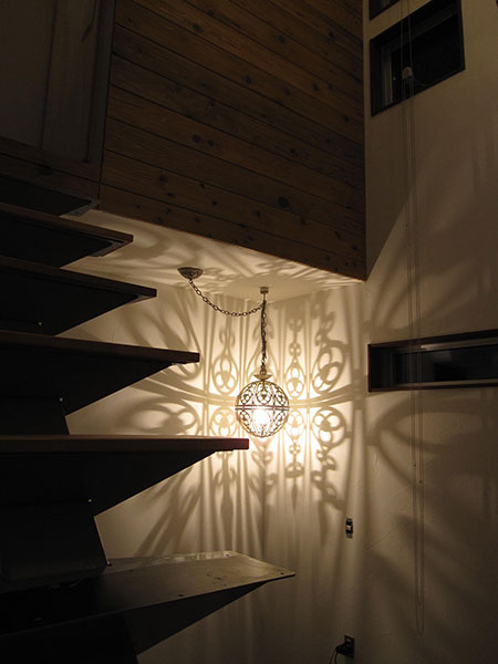 階段下空間に装飾照明を設置し、陰影を活かした落ち着きのある内装デザイン