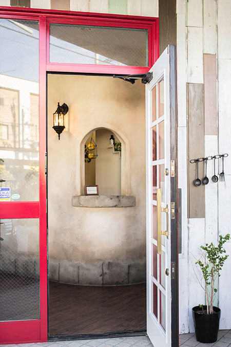 店舗入口のドアを開けた先に、アーチ型ニッチと照明が見える雰囲気ある内装デザイン